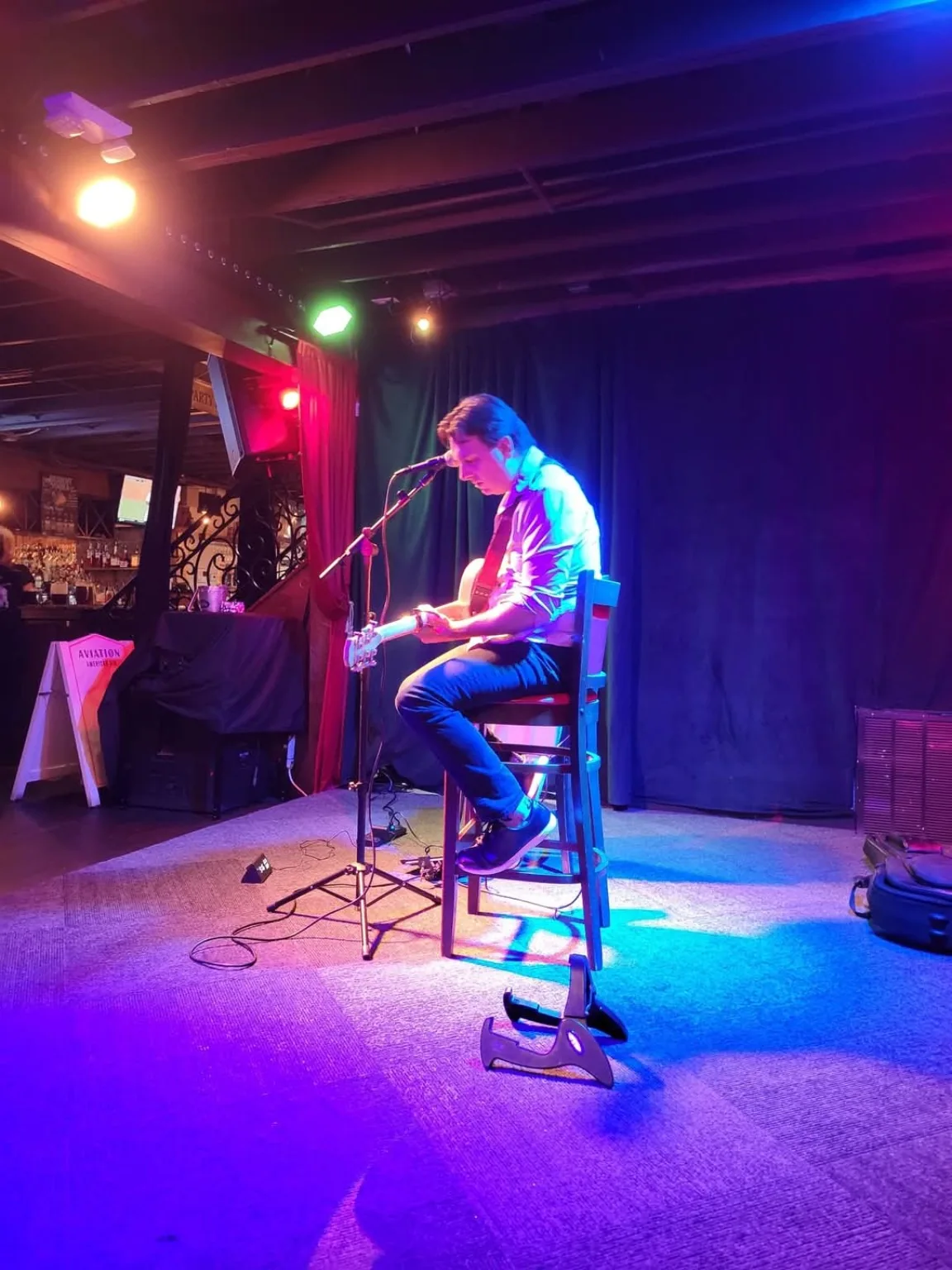 Dan Ennis playing guitar on a stage with colorful lighting