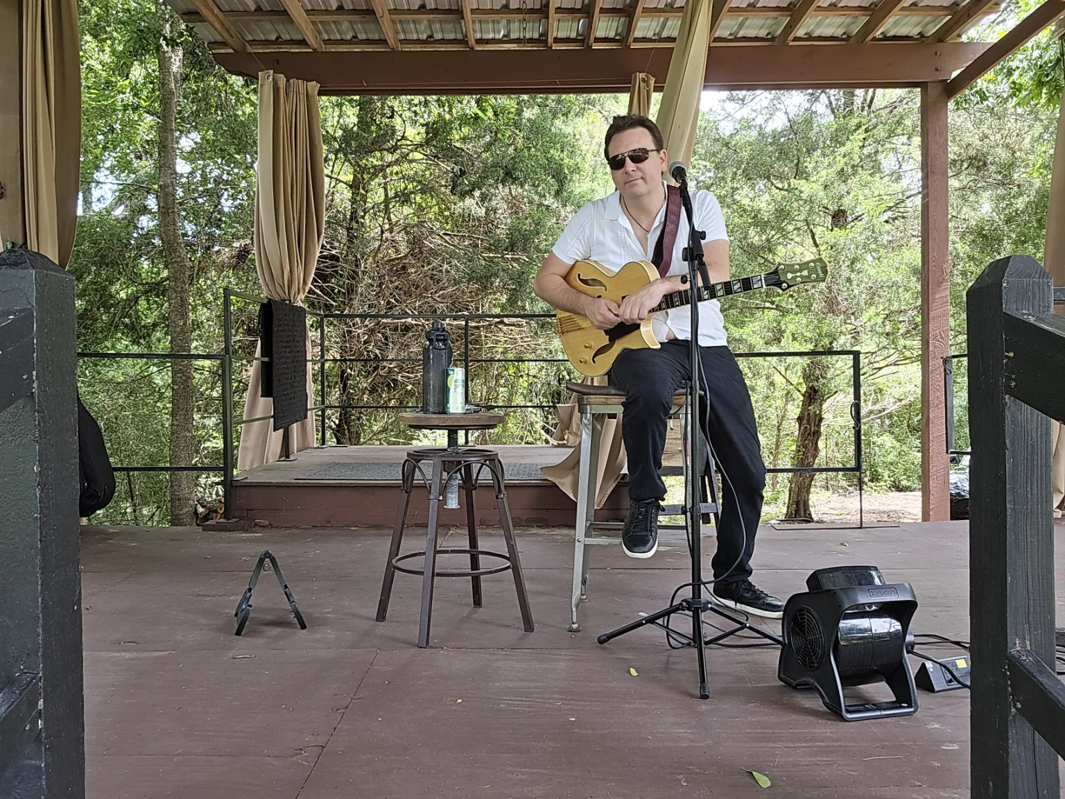 Dan Ennis seated with his guitar at an outdoor venue